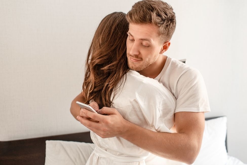 Mand ser i mobil mens han krammer kvinde