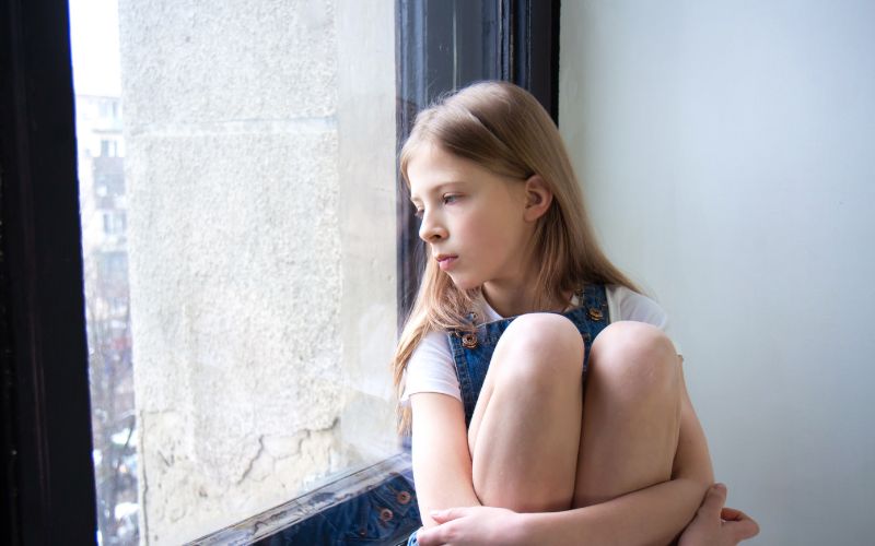 Eftertænksom pige ser ud ad vinduet – barn i skilsmisse