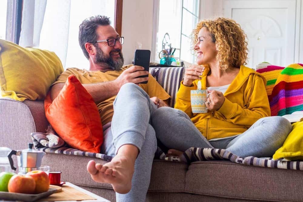 Par sidder afslappet i sofaen med te og snak – kærlighedssproget tid sammen