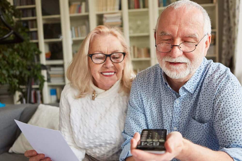 Ældre par samarbejder og hjælper hinanden med papirarbejde og lommeregner – et billede på kærlighedssproget tjenester